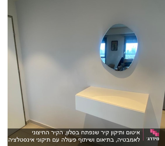 קיר עם מראה עגולה ושידה לבנה